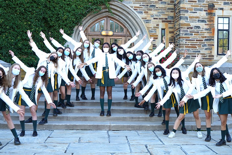 Grade 12 Prefects and School Captain in Number One Uniform posing with their arms open on the front steps of the Upper School.