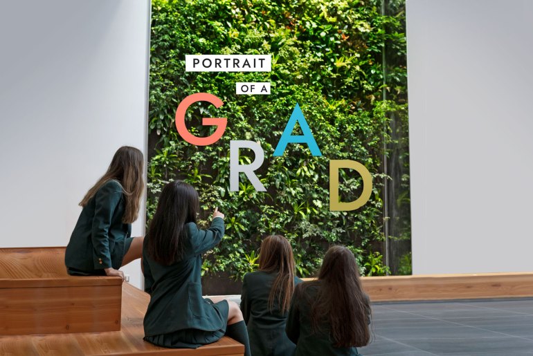 Students looking at the BioWall with the words "Portrait of a Grad" written on it.