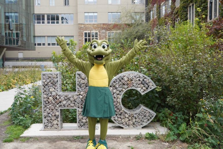 The Gator standing in front of the HC sign.