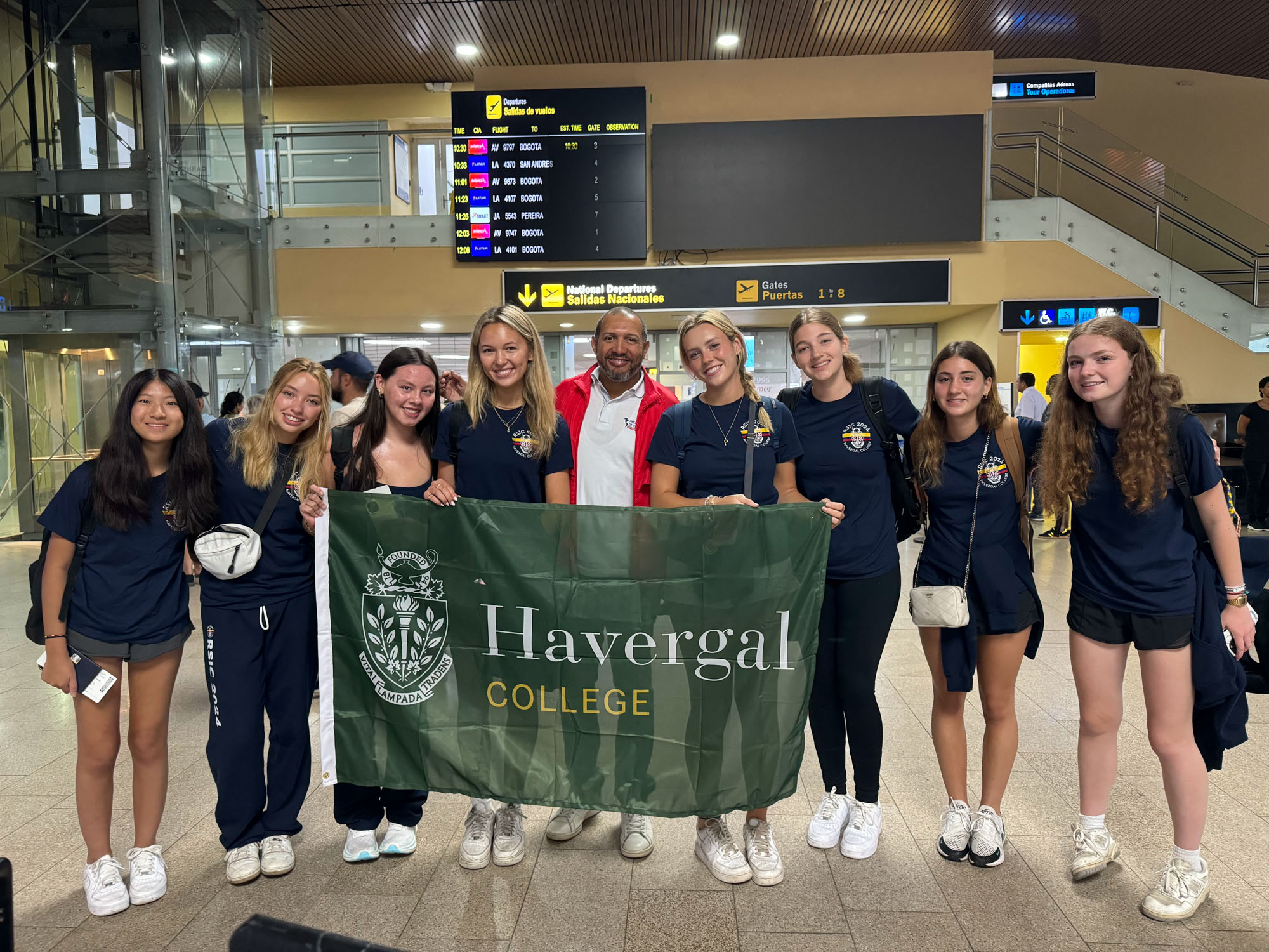 Students holding a flag that says "Havergal College" with their tour guide in Colombia.