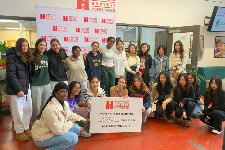 Students Speak Students at the North York Harvest Food Bank holding a sign that says "Today our team sorted 5.225 lbs. of food for our community."